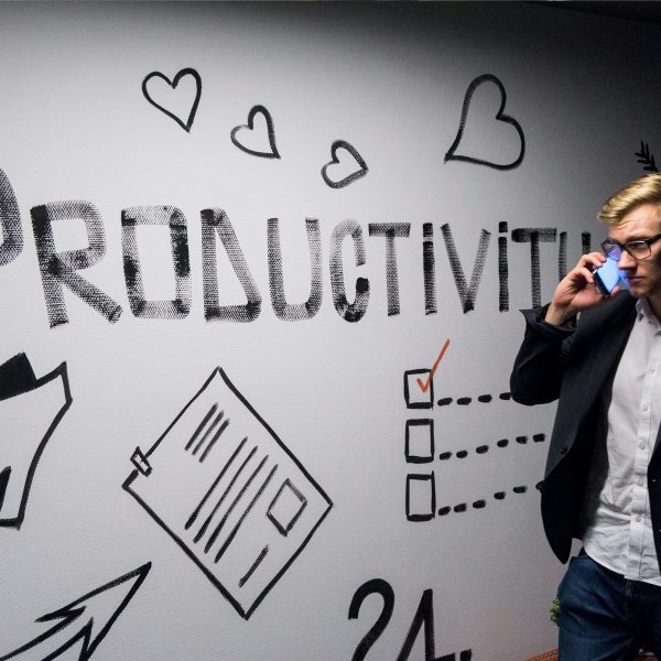 Employee walking past "productivity" signed wall