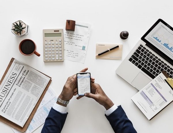 man reviewing his expenses on his phone at an office desk